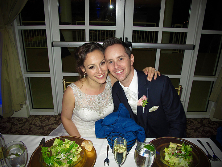 A Bride and Groom smile for the camera at their Sweetheart Table at the reception.