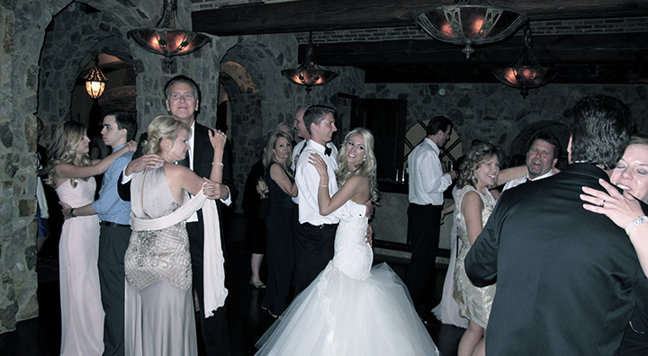 The wedding couple share a dance with their wedding guests at their reception.