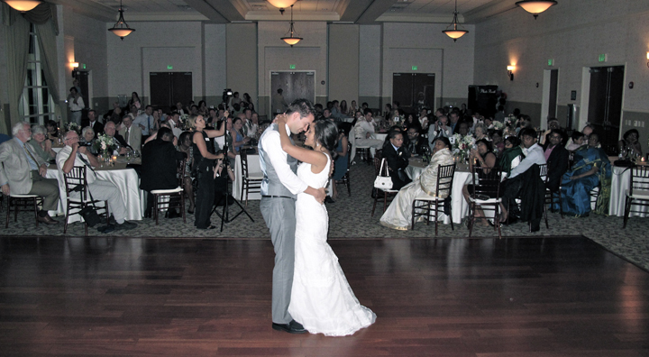 A Wedding couple share their First Dance at their reception as their guest look on.