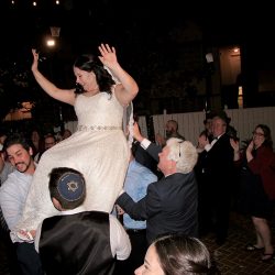 The bride is lifted on her chair during the Hora Dance at the Courtyard at Lake Lucerne