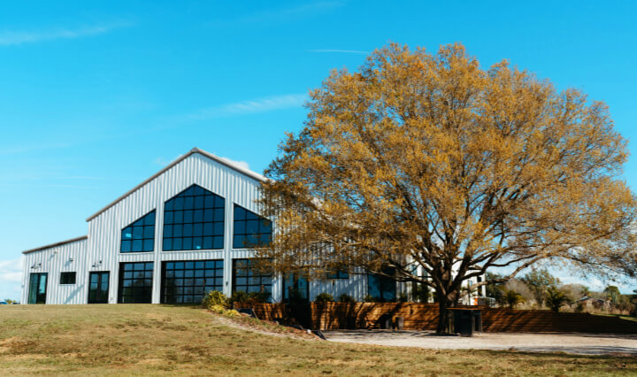 exterior view of hte Lavender on the Lake Wedding Venue with Cocktail Hour location under the oak tree